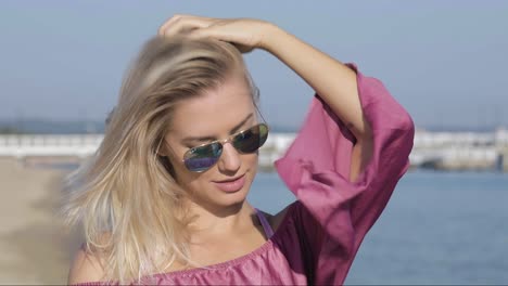 candid portrait of a gorgeous blonde woman adjusting her hair at the beach