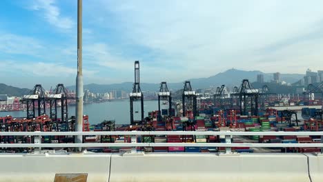 daytime drive-by of busy hong kong shipping port with gantry cranes and numerous containers