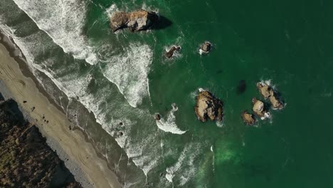 Top-down-aerial-view-of-California's-sandy-coastline-with-rock-islands-in-the-water