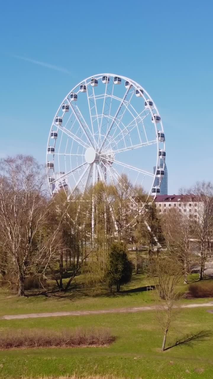 White ferris wheel and Riga skyscraper in background, aerial vertical view