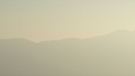 Panning-Time-Lapse-of-Sun-Setting-Behind-Mountain-and-Heavy-Atmosphere