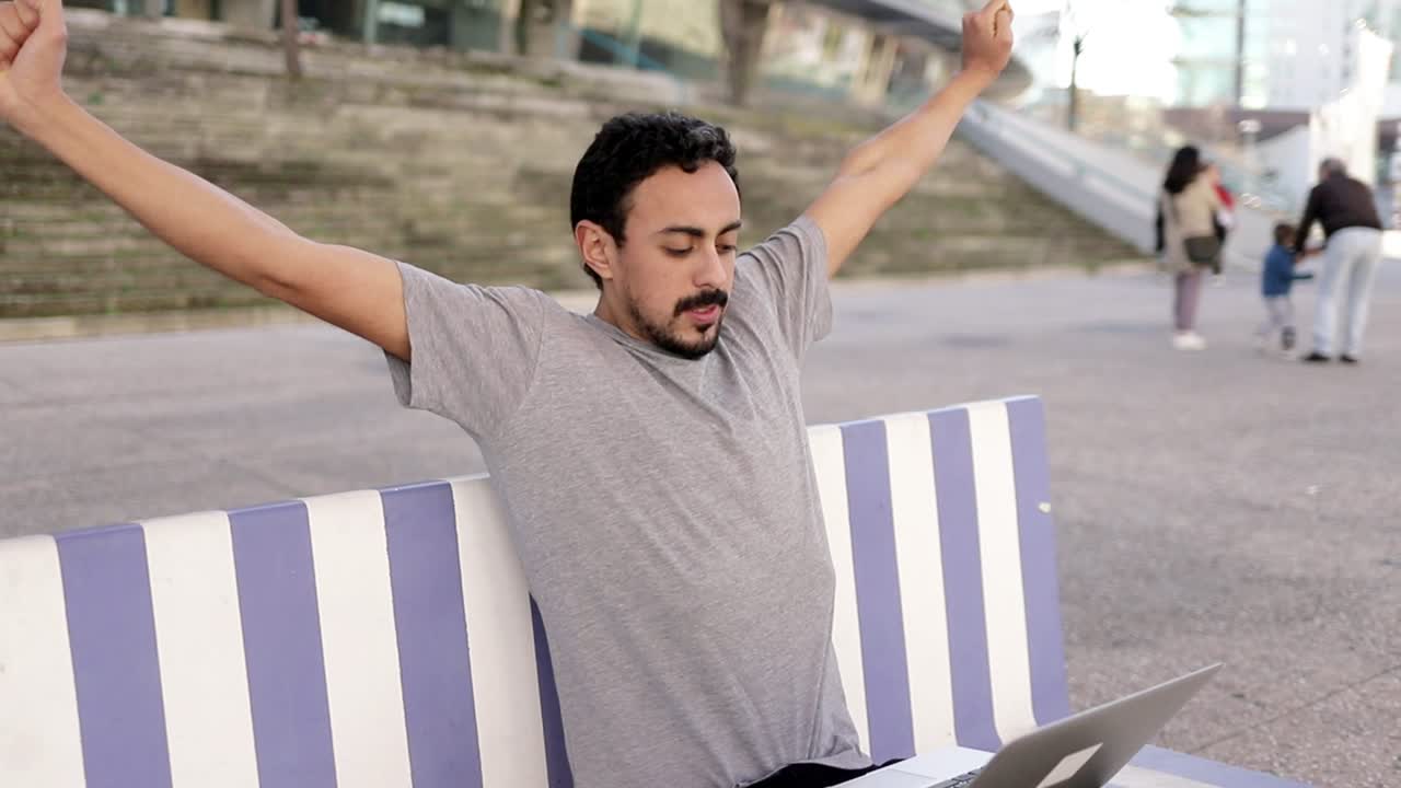 팔을 펴고 거리에서 노트북을 사용하는 남자