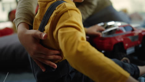 Boy-playing-toy-car-indoors.-Elder-brother-hands-grabbing-younger-brother.