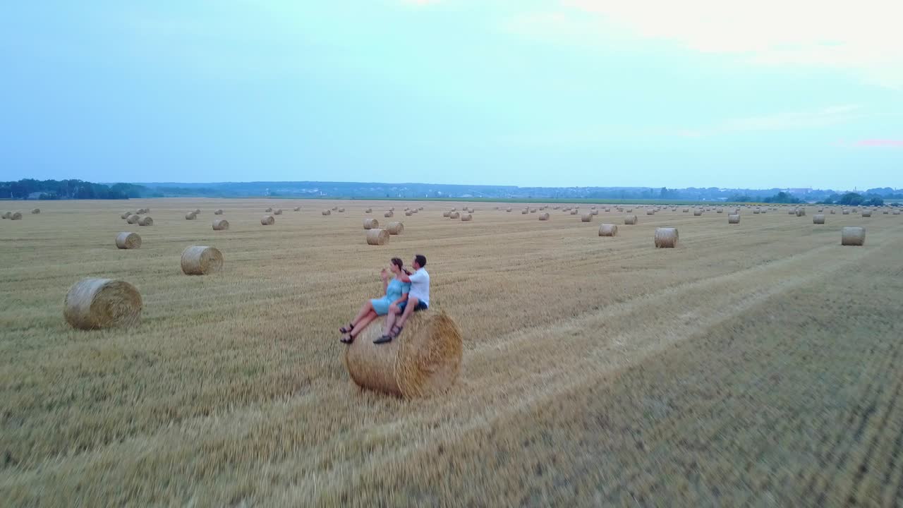 Couple Near Haystack At Countryside. Young lovely couple walking among the haystacks