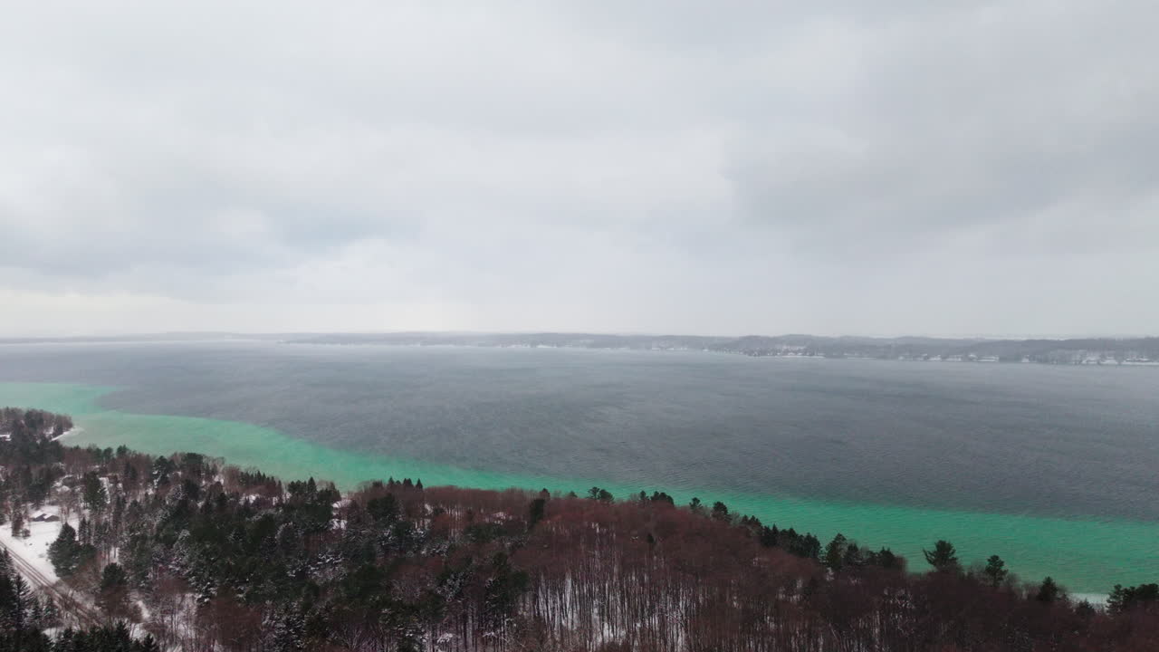 Højvinklet droneoptagelse af sne og vind, der fejer hen over Torch Lake, Michigan, midt om vinteren. Optaget i 4K 60fps.