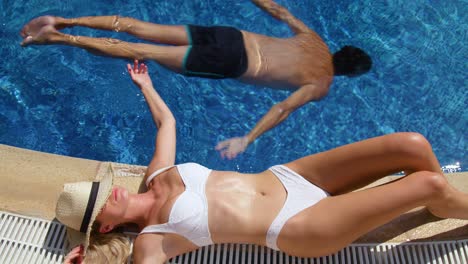 young woman sunbathing on poolside in resort