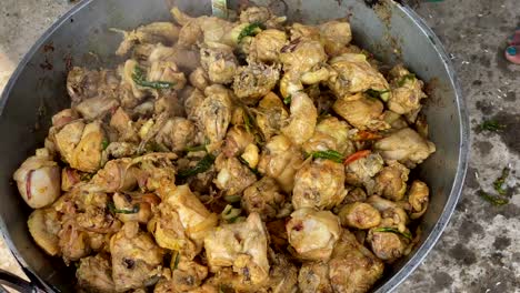 Cooking-chicken-meat-and-spices-together-in-a-large-pot-over-a-fire-outdoors-with-heat-waves-shimmering-over-the-pot