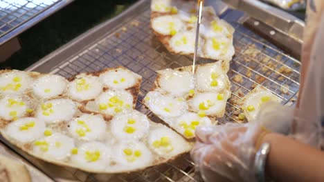 Porcionar-Y-Cortar-Comida-Callejera-Tradicional-Tailandesa-Desierto-Khanom-Krok-Con-Relleno-De-Maíz,-Tortitas-De-Harina-De-Coco-Y-Arroz