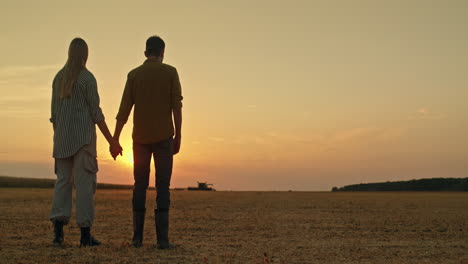 una pareja mirando el atardecer sobre un campo cosechado