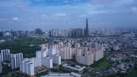 aerial fly in to large modern residential development with city skyline in background on a sunny day in ho chi minh city, vietnam