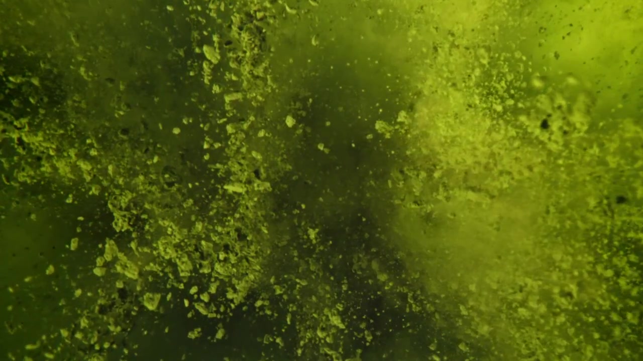 Polvere verde vibrante che esplode e si diffonde nel liquido