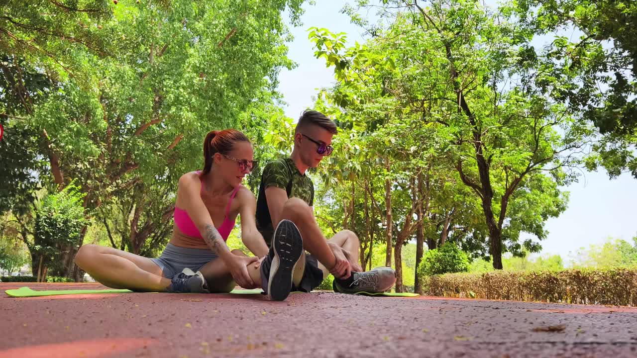 una pareja estirándose en el parque.