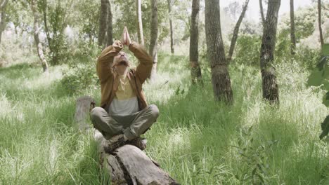 Hombre-Afroamericano-Sentado-En-El-Tronco-De-Un-árbol-Y-Meditando-En-El-Bosque,-Cámara-Lenta