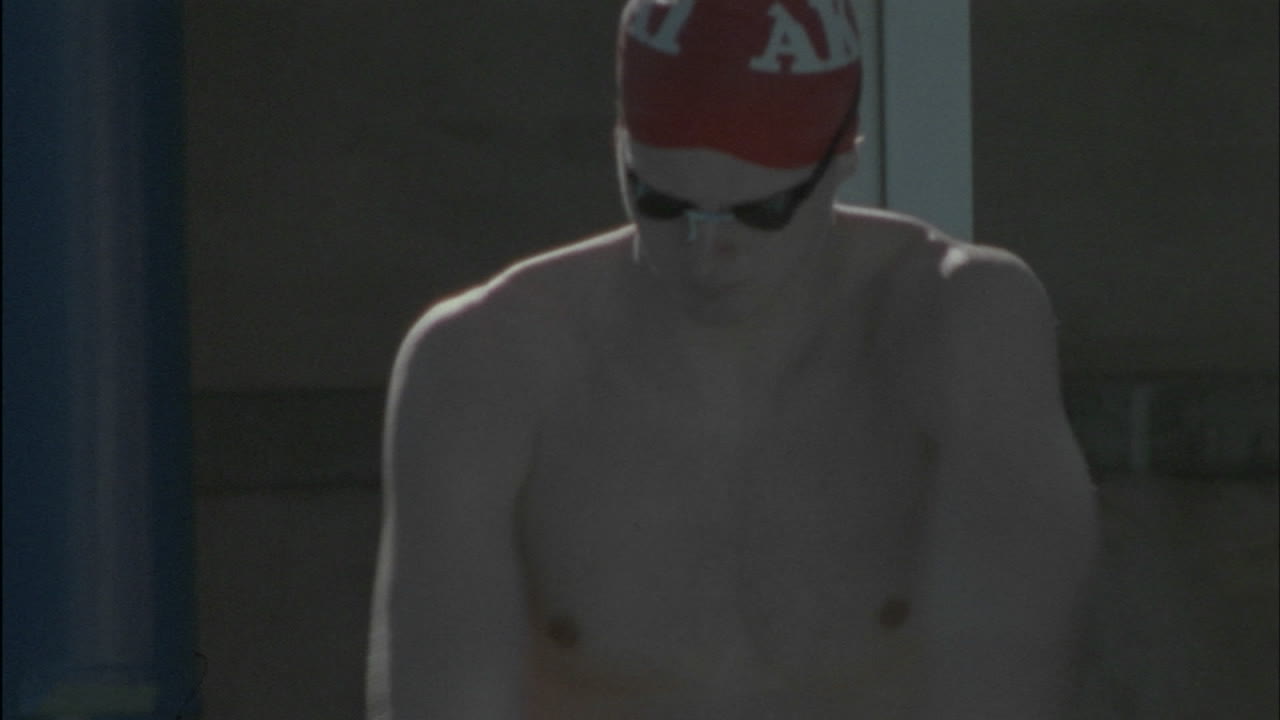 un nadador masculino se calienta y luego se sumerge en la piscina