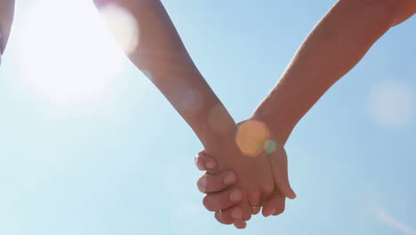 un primer plano de una pareja tomándose de la mano en la playa