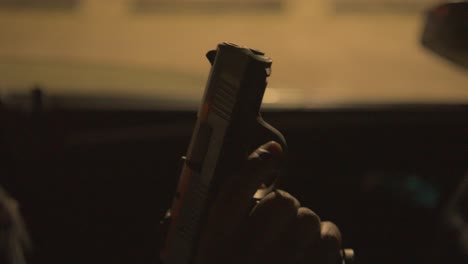 close up of a black man in the drivers seat of a car ejecting a bullet from his handgun