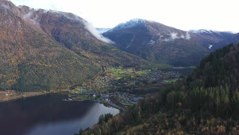 town of kinsarvik disappearing behind lush autumn hillside - backward moving aerial from hardanger norway