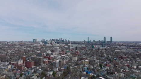 Forwards-fly-above-streets-and-buildings-in-residential-urban-neighbourhood.-Skyline-with-modern-tall-buildings.-Boston,-USA