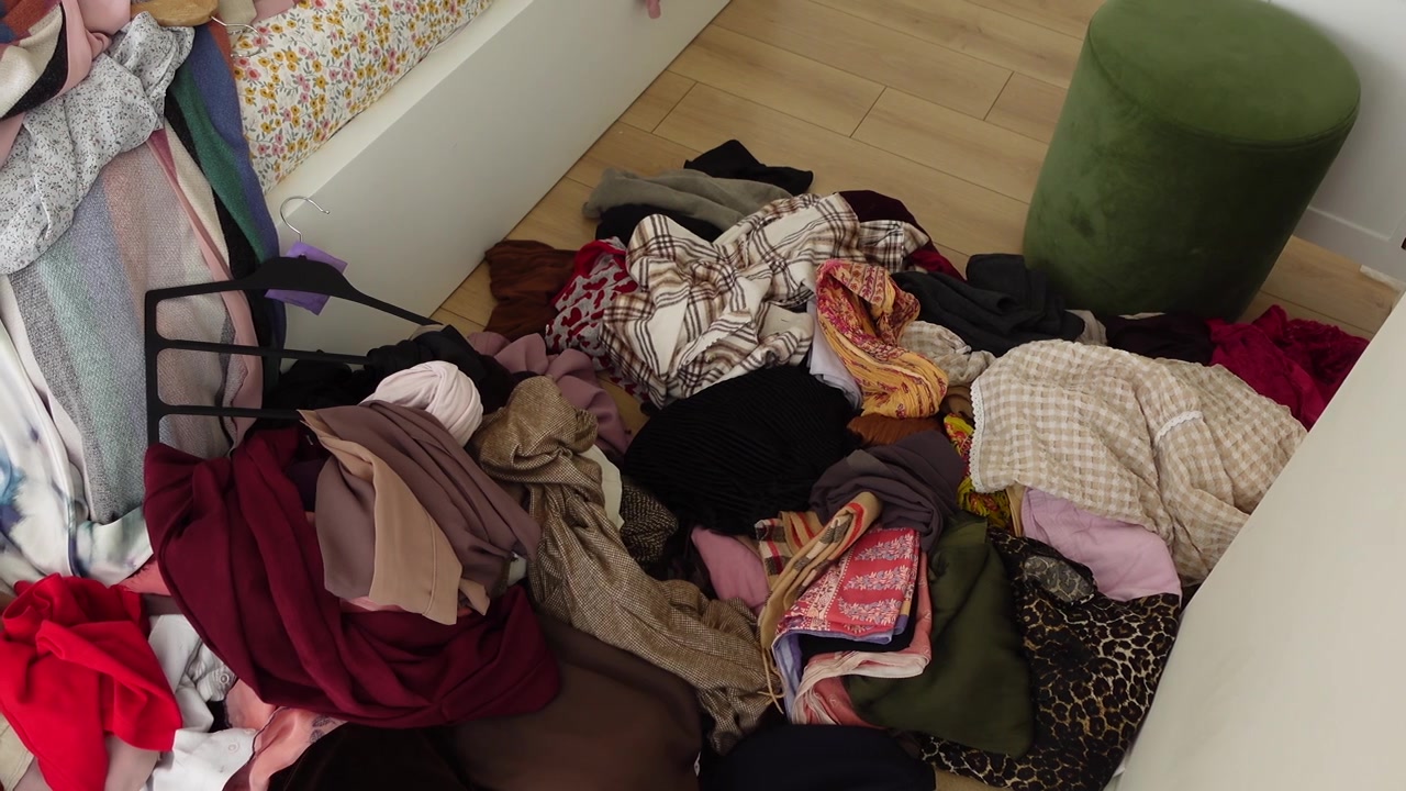 Large Pile of Messy Clothes on a Wooden Floor