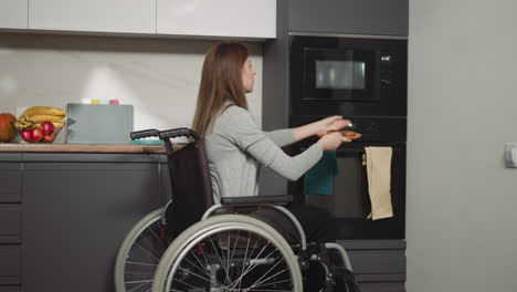 young woman with injury puts food into microwave and waits