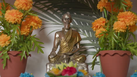 buddhist statue on a shelf in between orange flowers