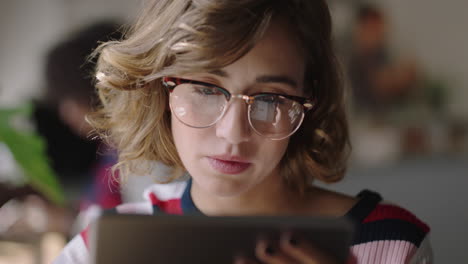 close up young caucasian woman using digital tablet computer in cafe drinking coffee student enjoying watching online entertainment reading social media on portable device wearing glasses