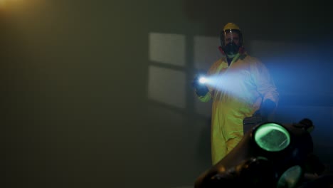 hazmat suit wearing man explores a dark room