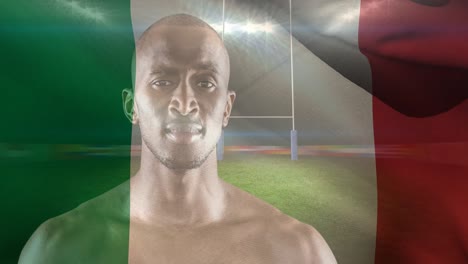 animación de la bandera de italia sobre un jugador de rugby afroamericano con una pelota en el estadio