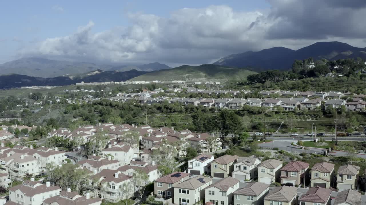 Descending aerial of neighborhood of homes in suburb of Los Angeles, dark clouds in distance