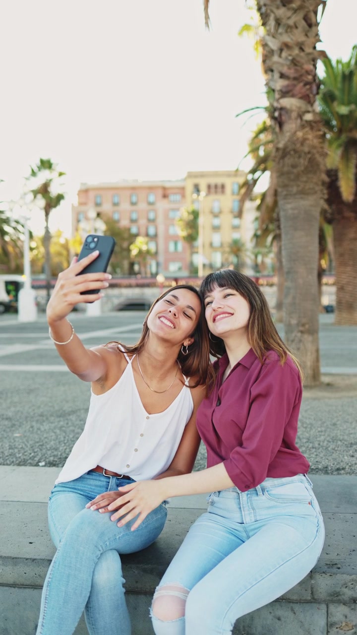 Mujeres jóvenes sonrientes tomándose una selfie juntas en un parque urbano