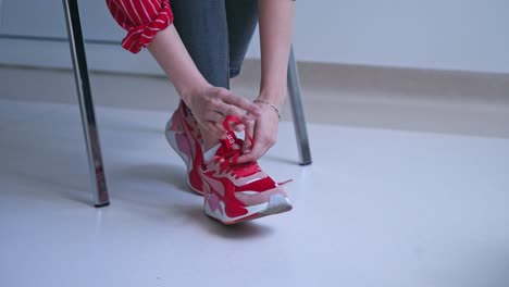 woman tries to tie shoelaces on sneakers. young woman feels pain in hands. problems with hand joints. close-up.
