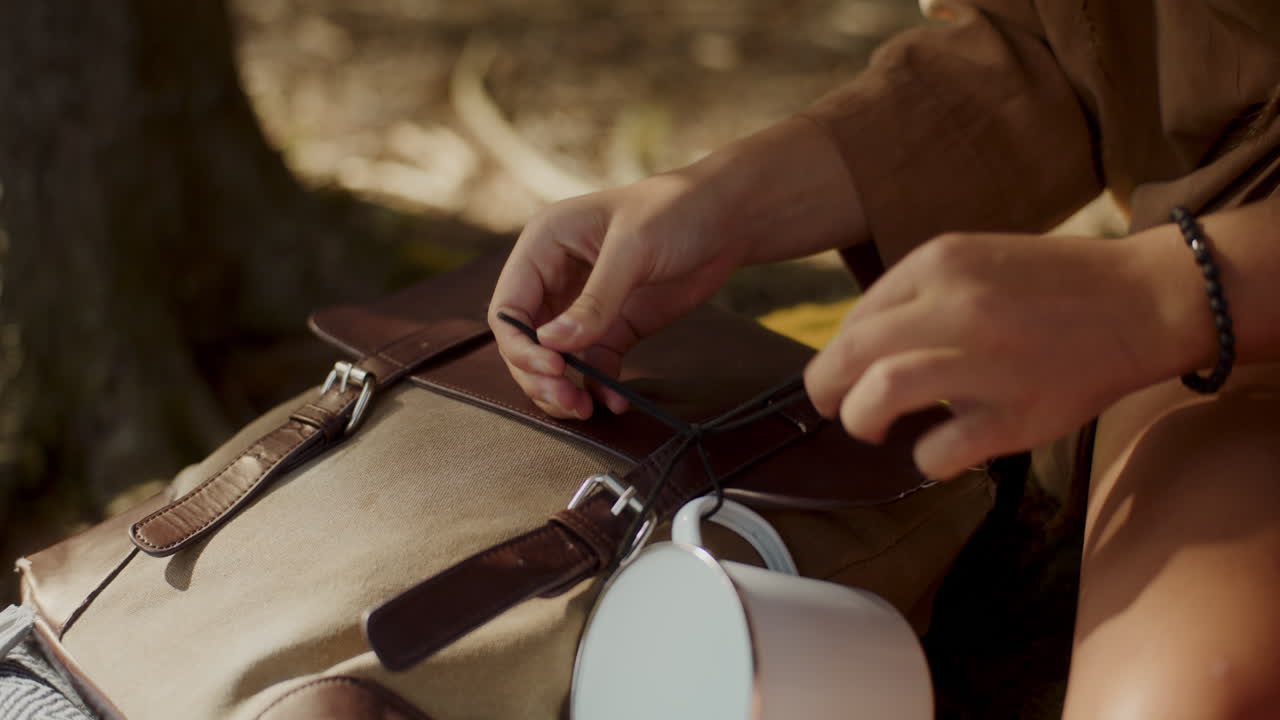 mujer atando taza de viaje con mochila en el bosque