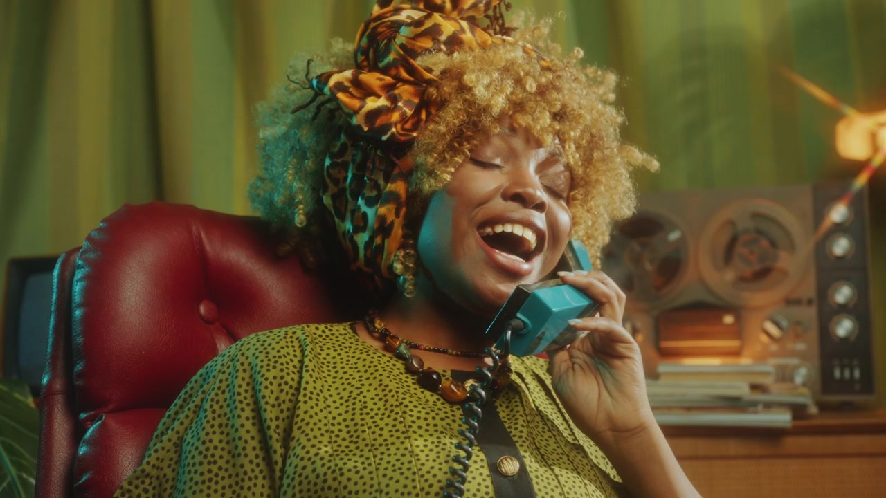 Giovane donna afroamericana sorridente che parla al telefono fisso retrò
