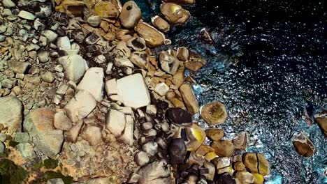 rocky shoreline with dark ocean water top down drone view