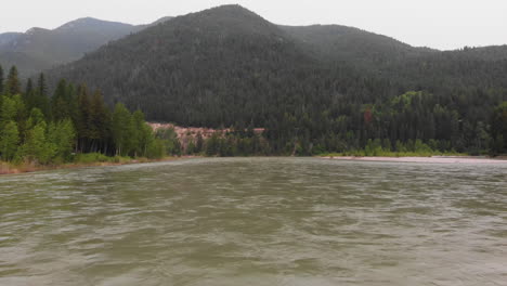 aerial shot of the middle fork flathead river, camera moves forward close to the water and towards mountains and pine forest in the background