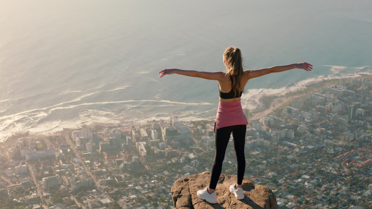 mujer joven con los brazos levantados en la cima de la montaña celebrando el logro niña en el borde del acantilado mirando la hermosa vista disfrutando de viajes aventura libertad