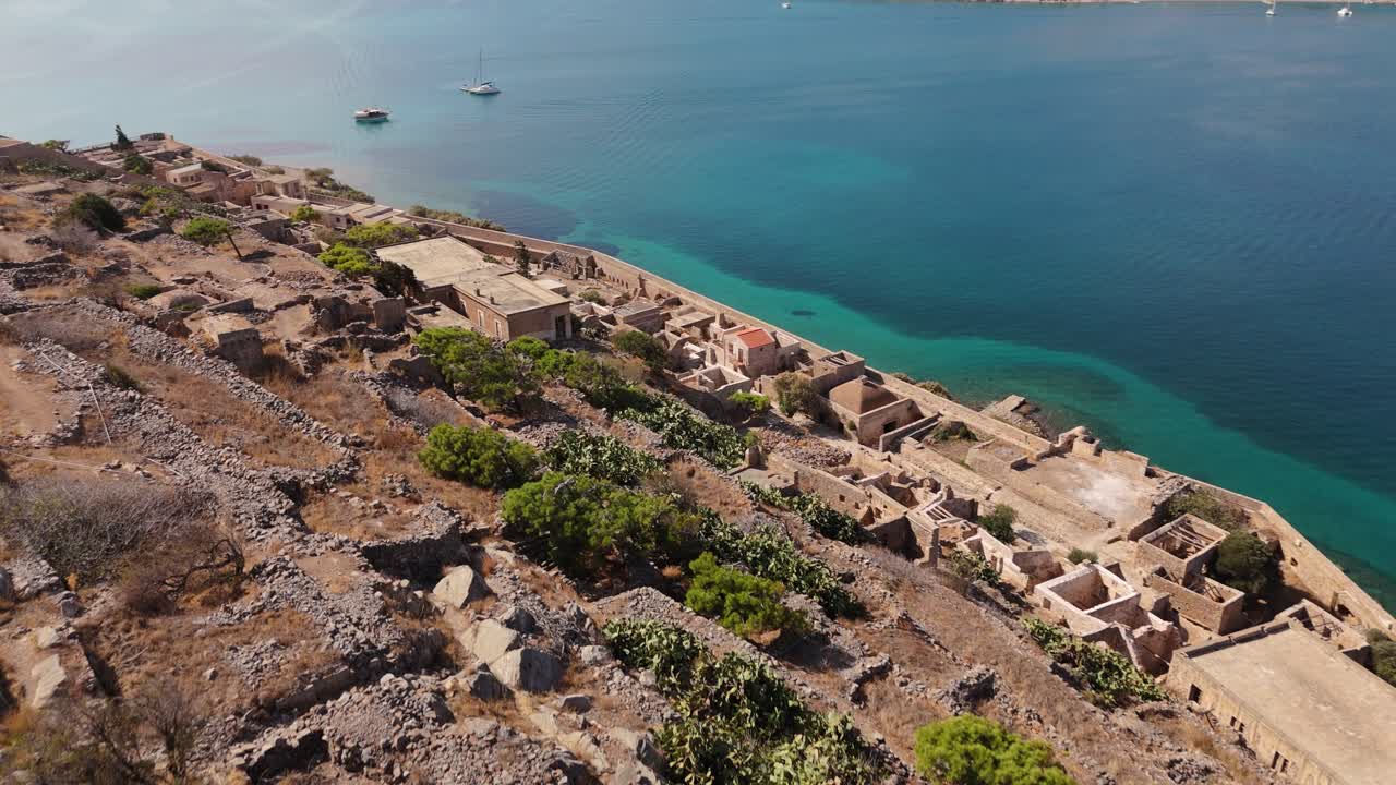 드론은 스피날롱가 (spinalonga) 의 역사적인 폐허를 따라 절벽을 넘어 블루 베이 (blue bay) 의 광활한 전망으로 내려갑니다.
