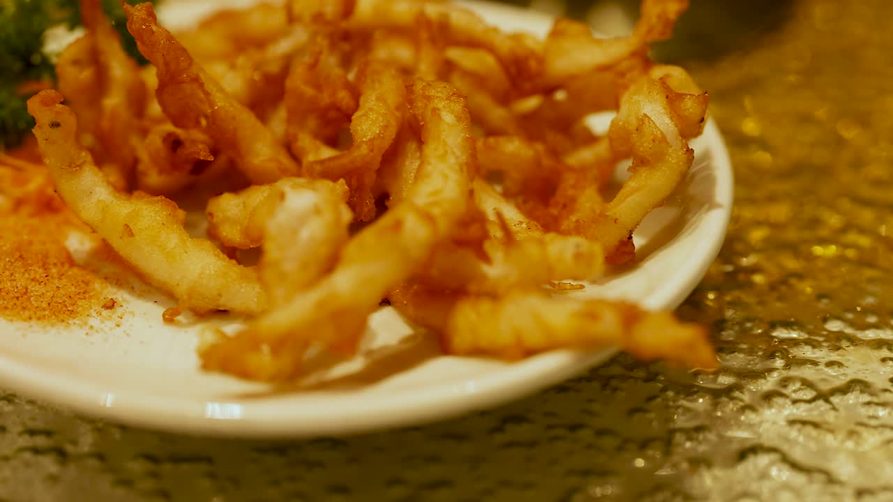 Snack dorati fritti su un piatto con guarnizione, ripresi con illuminazione calda in un ristorante cinese