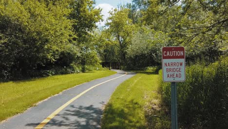 Beautiful-bike-path-that-leads-to-a-narrow-bridge-over-a-small-creek