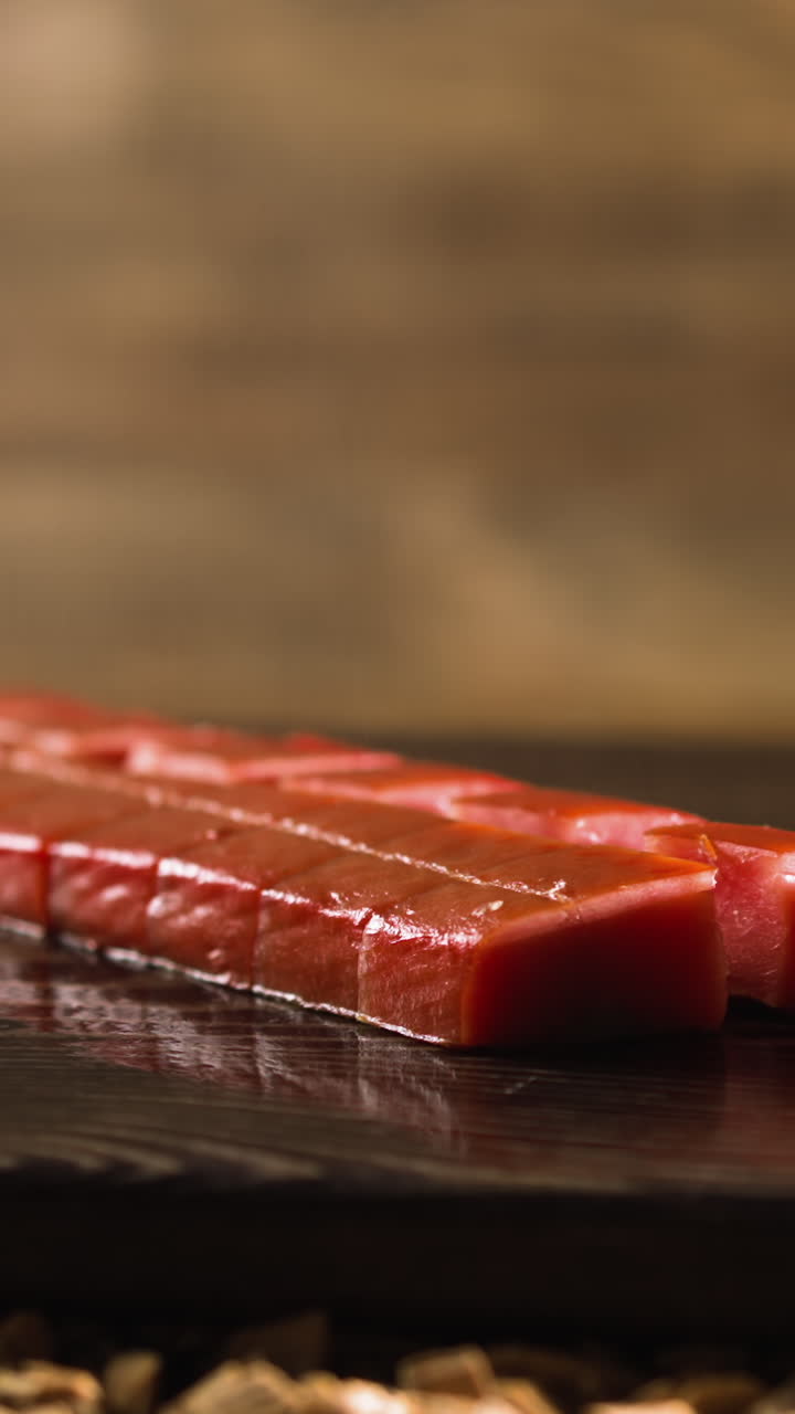 Cut fillet of delicatessen smoked red fish chum salmon served on rustic wooden tray lying on wooden chips pile in smokery closeup slow motion