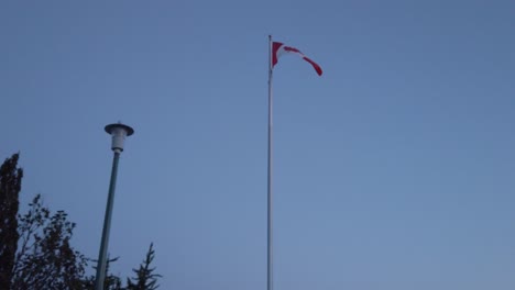 Slowmotion-view-landscape-zooming-view-into-the-Canada's-flag-while-wind-blowing-in-sunset-sky-time