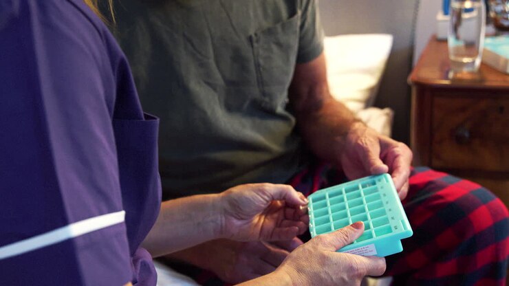 Primo piano di un'infermiera che aiuta un uomo anziano con i farmaci a casa