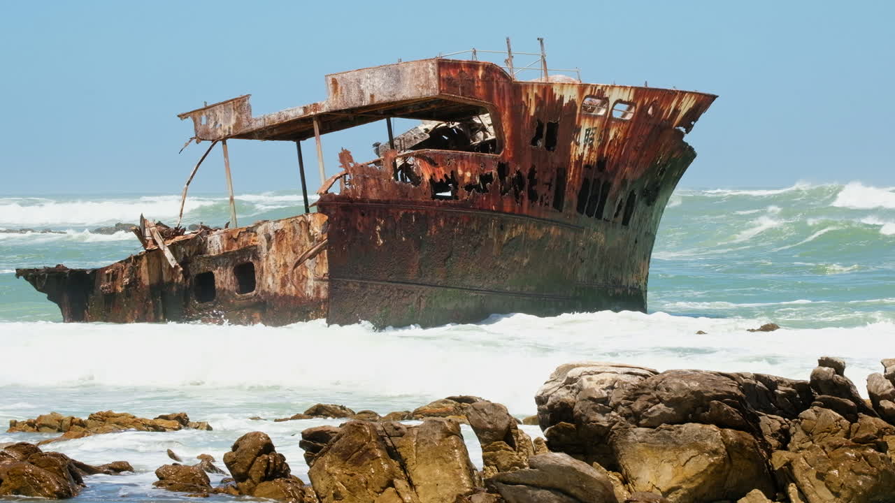 Rusty sunken shipwreck stuck in shallows of rugged Cape Agulhas coastline