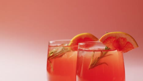 close up of drinks with oranges on pink background