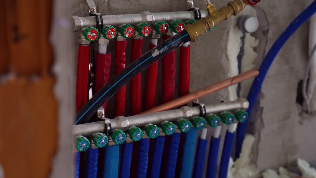 Color-coded heating and water manifold with blue and red pipes in utility wall installation