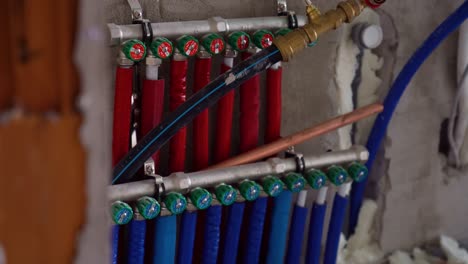 color-coded heating and water manifold with blue and red pipes in utility wall installation