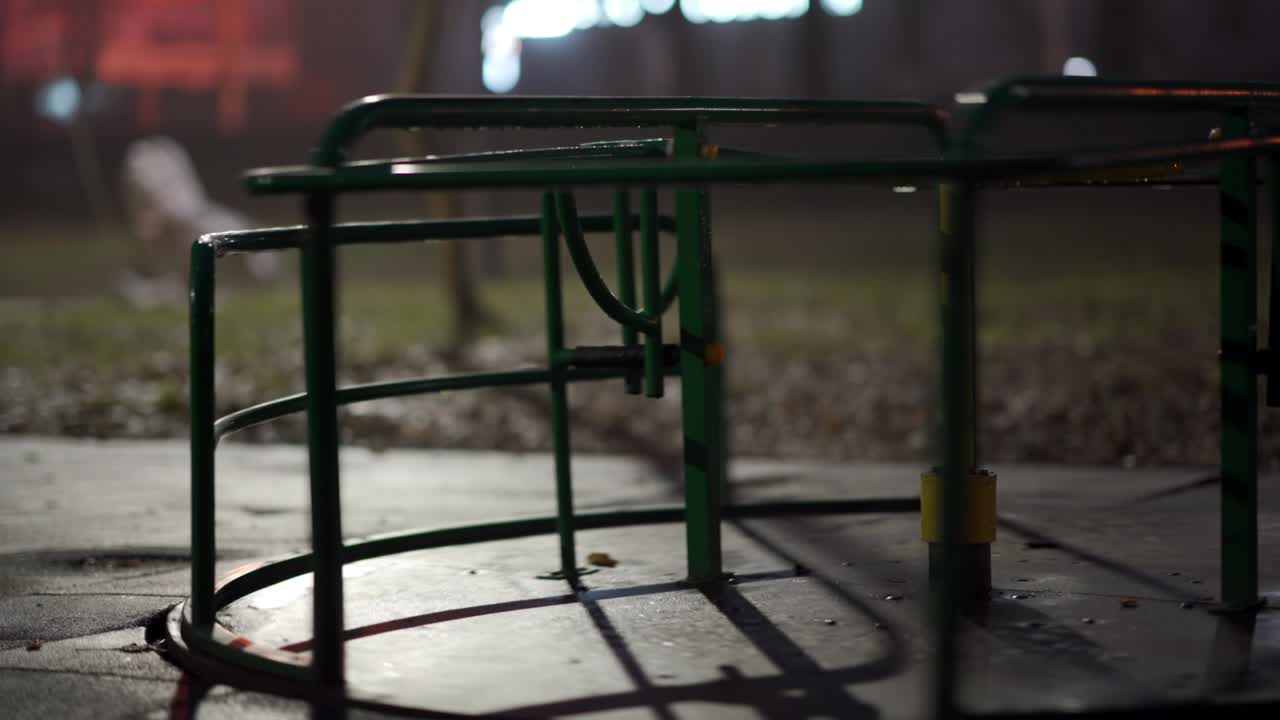 가을 밤에 시내 공원의 빈 어린이 놀이터에서 은 카루셀이 회전하고 있습니다.