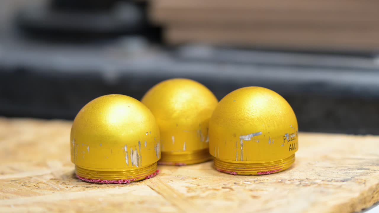 Yellow grenade casings, prepped for drone attachment with plastic modification, are displayed at a workshop in Ukraine's Donetsk region. Adaptive weapon tech for modern combat.