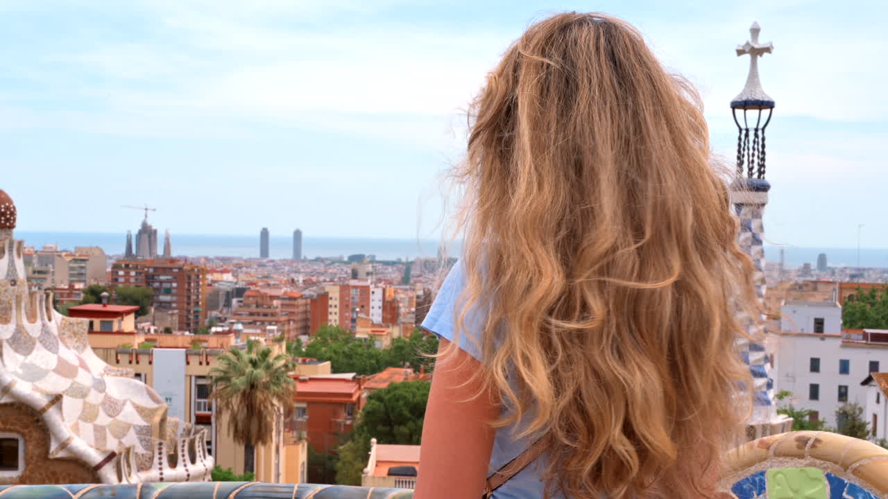 Barcelona, Spanien – 26. August 2022: Blonde Frau betrachtet architektonische Elemente im Park Güell von einer Terrasse aus