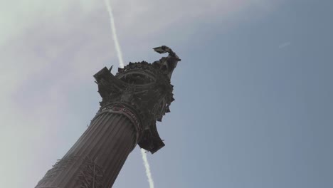 Christopher-Columbus-Statue-with-big-blue-sky-background-and-cloud-trail-from-a-plane-in-Barcelona